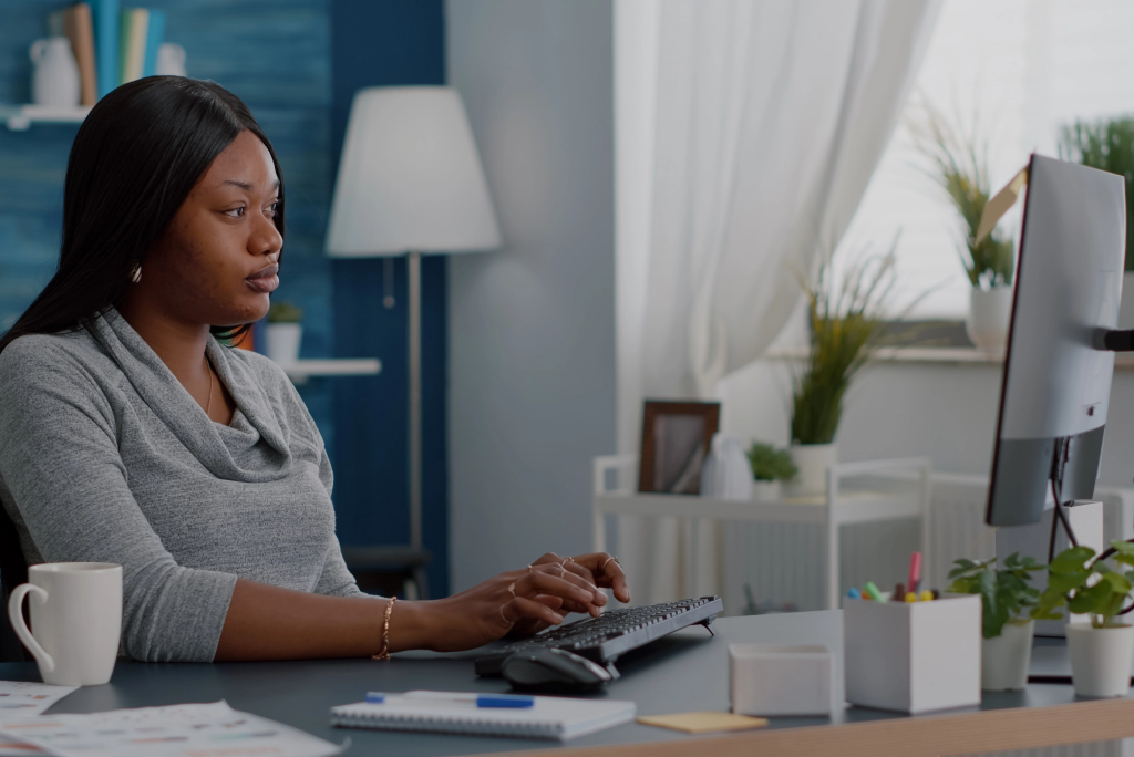 Worried displeased black student massage forehead having headache while working remote from home siting at desk browsing medical pain treatment on com