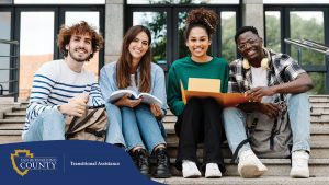 Four college students sitting together on stone steps outside a campus building.